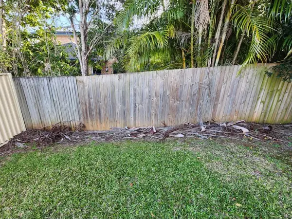 Fallen branches and garden debris cleared along a timber fence line