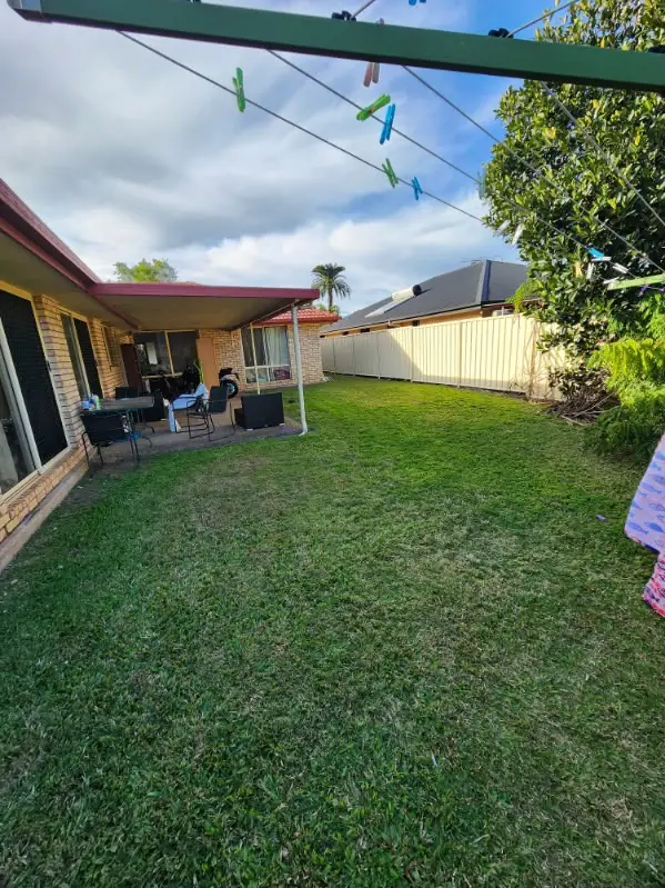 Mown backyard lawn beside an alfresco setting and covered patio