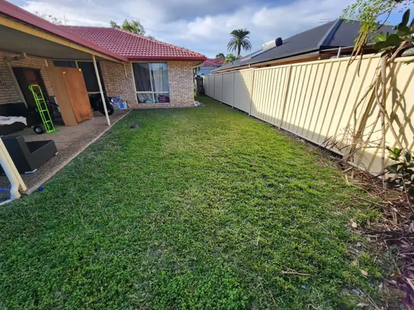 Backyard lawn mown along a covered patio and Colorbond fence