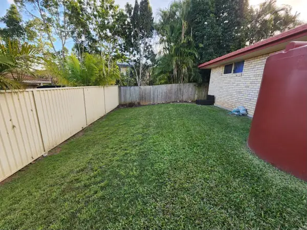 Backyard lawn mown clean around a rainwater tank and boundary fence