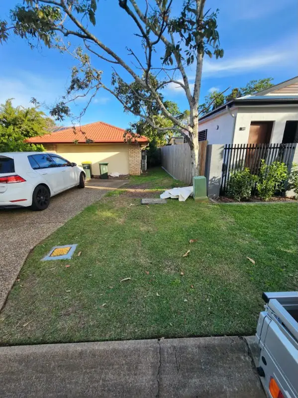 Side lawn mown clean alongside a gravel driveway and gate
