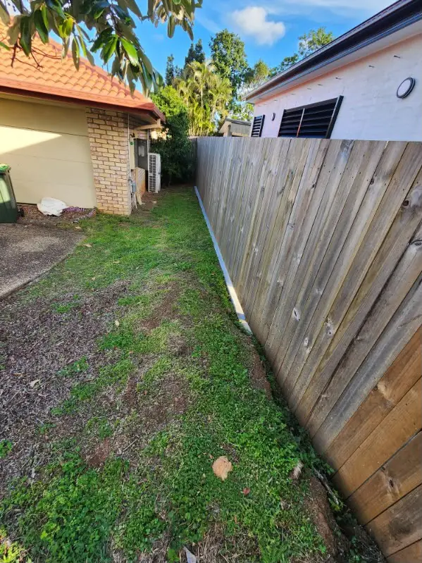 Side yard mown and tidied along a timber fence in dry winter conditions