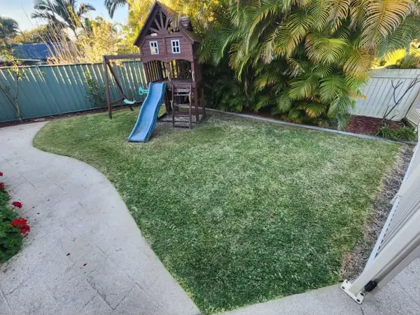 Backyard lawn mown in clean stripes with sharply edged concrete path
