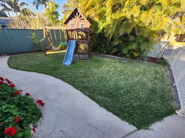 Family backyard mown and edged around a play fort, with crisp edges along the garden bed
