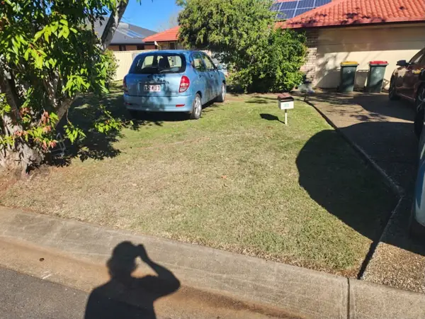 Front lawn mown up to a driveway and carport