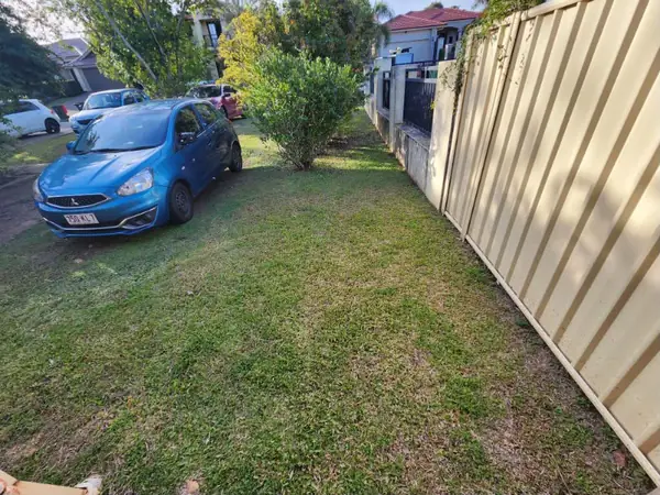 Side yard lawn mown along a Colorbond fence beside a driveway